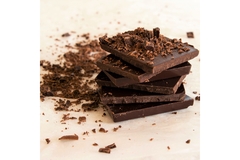 Stack of dark chocolate pieces with chocolate shavings on top.